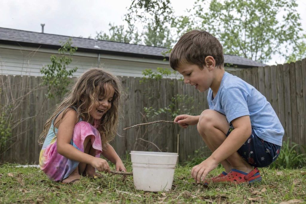 Two young children playing in a backyard photographed at their eye level