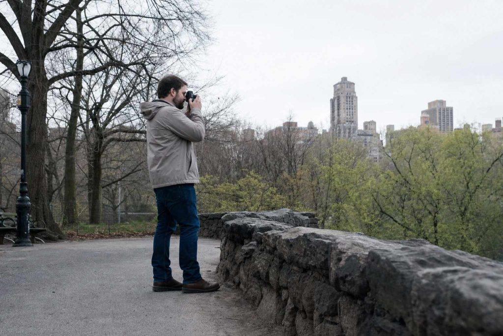 A person photographing in soft overcast light in a city park