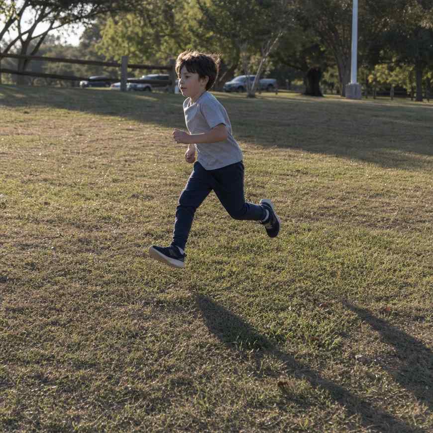 A child running across grass in warm low side light casting a long shadow